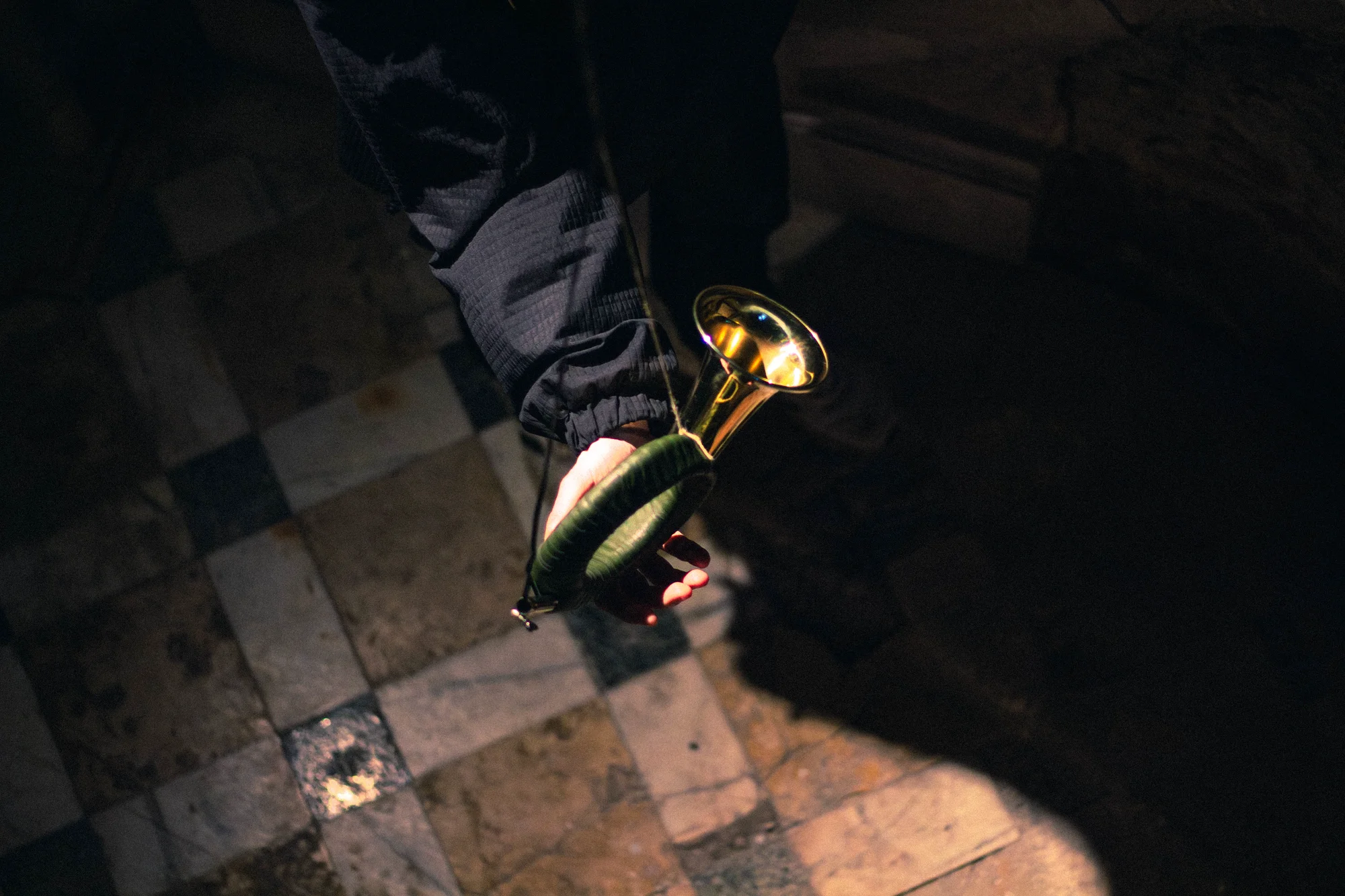 Overhead view of visitor holding the hunting horn on historic stone tile floor with dramatic spotlight, Hirsch Tot Dessau 2025